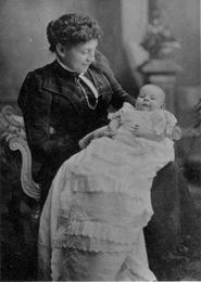 Vintage black and white photo of a lady holding a baby in a christening gown